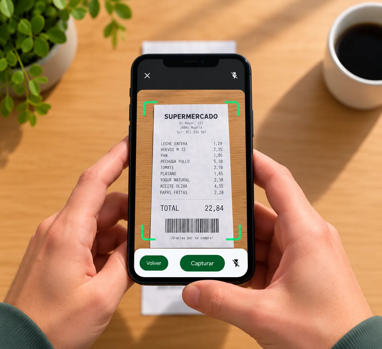Manos fotografiando un ticket de compra con un teléfono sobre una mesa de madera.